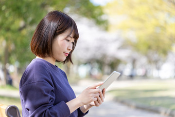 Fototapeta premium 春の公園のベンチでくつろぐ女性