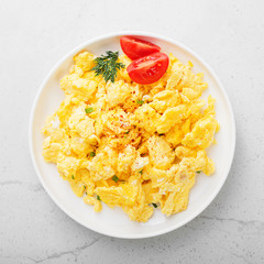 Scrambled eggs on plate over gray stone background.