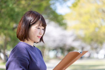 Fototapeta premium 春の公園のベンチでくつろぐ女性
