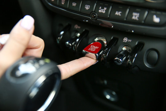female's finger presses the toggle switch to start the car engine. red toggle switch engine start close-up. start engine button