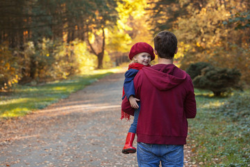 Obraz premium Father hugs daughter in autumn day. Back view, copy space.