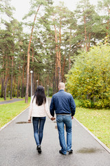 Fototapeta na wymiar A man and a woman walking down the alley in the Park, holding hands