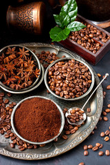 Coffee beans, milled coffee and spices on dark background