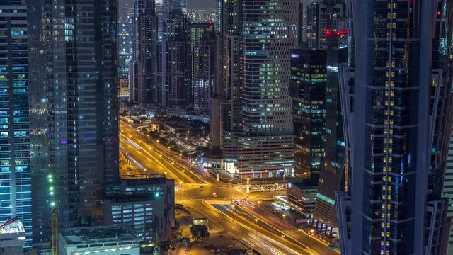 Luxury Dubai Marina canal with passing boats and promenade with restaurants night timelapse, Top view from above with illuminated skyscrapers. Dubai, United Arab Emirates