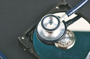 Data recovery or computer forensics concept, stethoscope dusty dismantle hard disk over dark background - 261469674