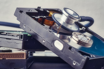 Data recovery or computer forensics concept, stethoscope dusty dismantle hard disk over dark...
