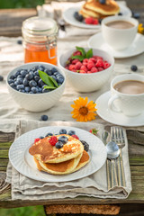 Tasty pancakes served with coffee in garden