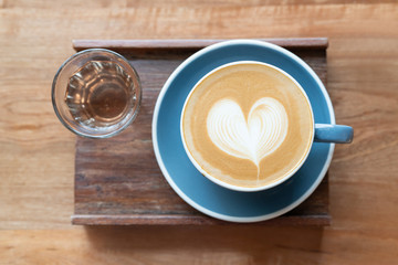 Top view of hot Coffee cup with a cup of tea by barista art heart shape foam on wooden table background.