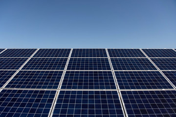 Obraz premium Close up solar panels on blue clear sky background producing friendly environment energy. Alternative electricity source. Space for text