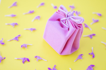 Pink gift box on a yellow background with flowers. Festive concept.  Flat lay, top view 