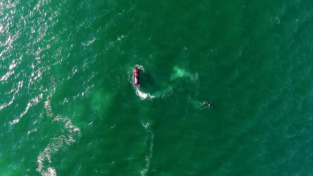 Acrobatics with flyboard in the ocean. A flyboard rider stands on a board connected by a long hose to a watercraft.