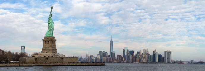 The skyline of New York City at daytime with the Statue Of Liberty National Monument in front.