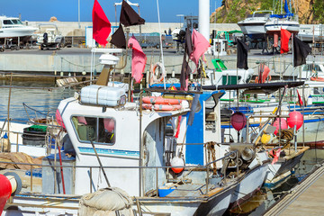 Fishing boats and private yachts moored at pier in seaport Blanes. Vessels with catch of sea fish delicacies. Sailing and motor boats are moored at concrete seawall. Marina Blanes, Spain, Costa Brava