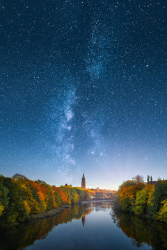 Ethereal image of fall foliage and Aura river with Turku Cathedral in Finland against beautiful milky way on the sky.