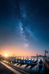 Gondolas against golden sunrise and with epic milky way on the sky