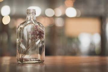 flower in the bottle on wooden table with light bokeh background in the restaurant