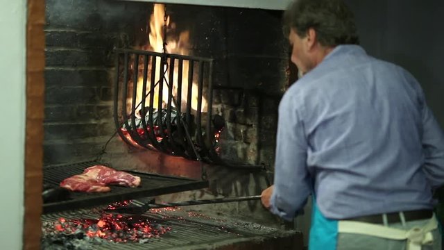 Man taking car of BBQ grill. Older person working in parilla grill