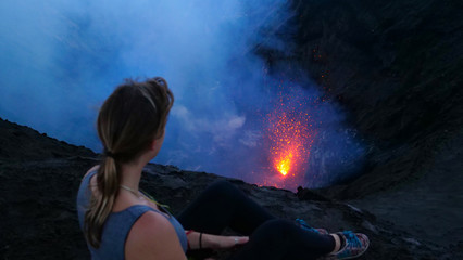 CLOSE UP: Young traveler woman sits on the crater rim of Mount Yasur in Vanuatu.