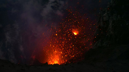 CLOSE UP: Glowing pieces of lava fly up in the air out of an active volcano. - obrazy, fototapety, plakaty