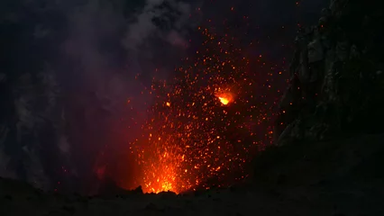 Fotobehang CLOSE UP: Glowing pieces of lava fly up in the air out of an active volcano. © helivideo