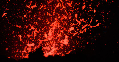 Fototapeta na wymiar CLOSE UP: Active volcanic crater spewing out pieces of bright orange magma.