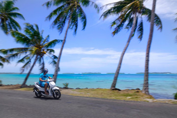 Young man having fun speeding along the scenic beaches of Bora Bora on a scooter
