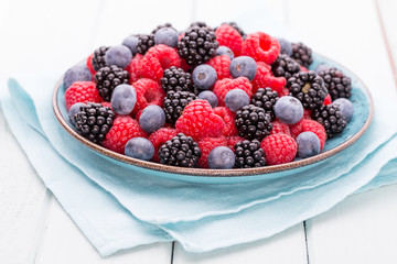 Fresh raspberries in a plate on a  vintage background.