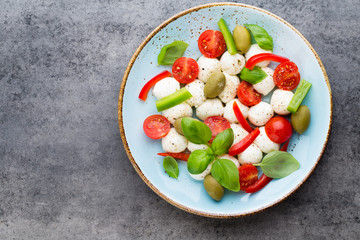 Delicious caprese salad with ripe cherry tomatoes and mini mozzarella cheese balls with fresh basil leaves.