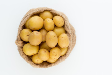 Sack of fresh raw potatoes on wooden background, top view