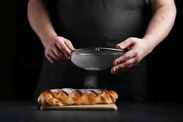 man in apron serving strudel on dark background. Baker cooking concept. recipe of baker