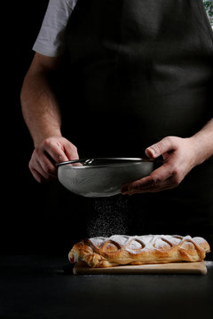 man in apron serving strudel on dark background. Baker cooking concept. recipe of baker