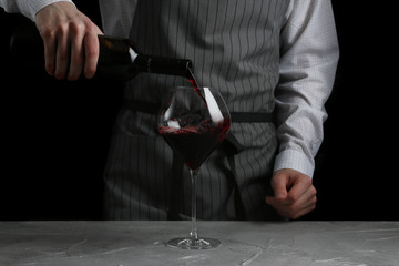 red wine pouring in glass. bartender on waiter concept on black background