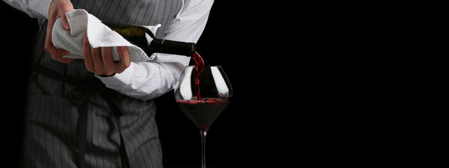red wine pouring in glass baner. bartender on waiter concept on black background