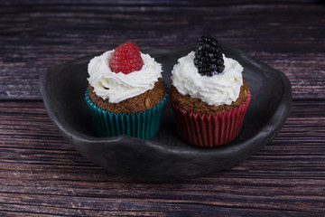 homemade muffin with raspberry and black clay dish on a rustik style wood table