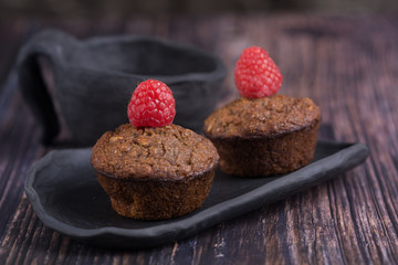 homemade muffin with raspberry and black clay dish on a rustik style wood table