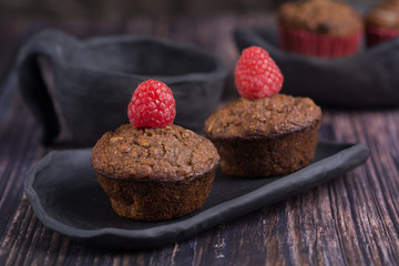 homemade muffin with raspberry and black clay dish on a rustik style wood table