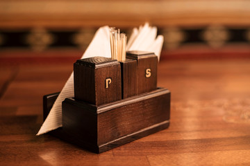 On a wooden table in the cafe there is a wooden box for pepper and salt with letters P and S