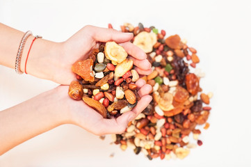 Nuts, dried fruits, dried bananas in the hands of the girl. Healthy food in the hands of every person