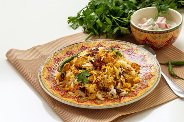 Halal Indian chicken Biryani served with yogurt tomato raita over white background. Selective focus.