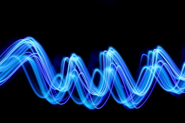 Blue light painting photography, long exposure, blue streaks of vibrant color against a black...