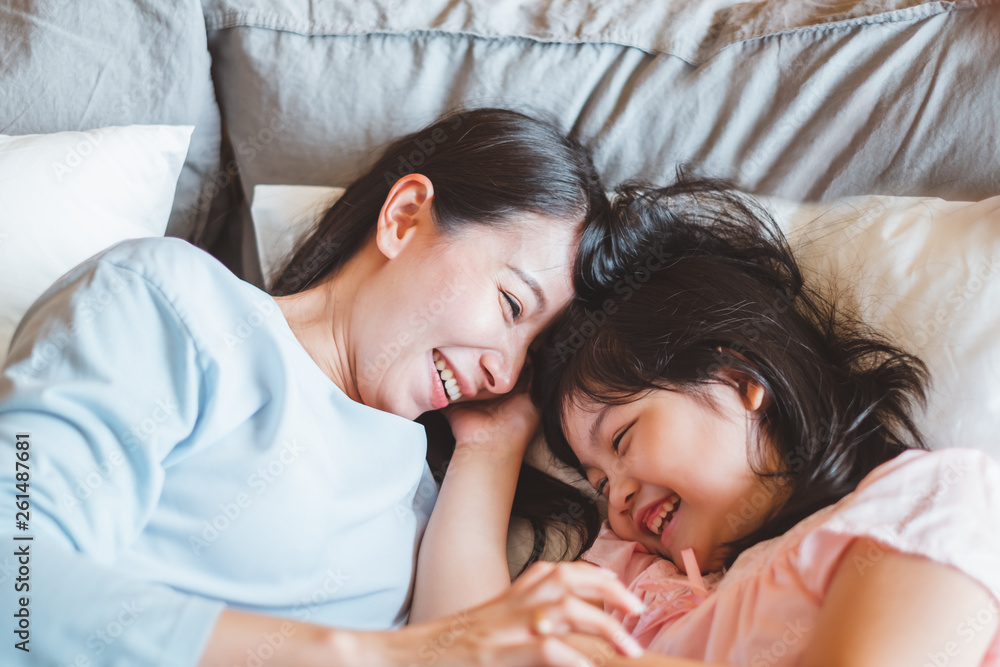 Wall mural Asian mother kissing daughter in bedroom, with love and warm family concept