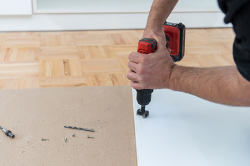 Carpenter milling the hole for the can hinge using forstner drill