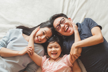 Happy Asian family laying on bed in bedroom with happy and smile, top view