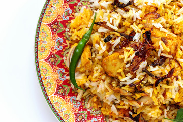 Halal Indian chicken Biryani served with yogurt tomato raita over white background. Selective focus.