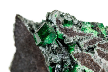 Macro stone garnet mineral, Uvarovite in rock on a white background