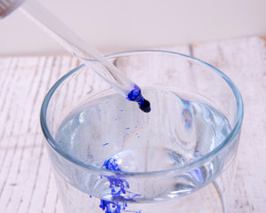 drop blue liquid with the pipette into a glass with water