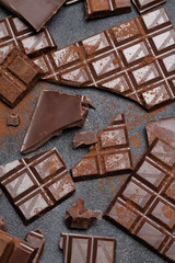 Dark or milk organic chocolate pieces and cocoa powder on dark concrete backgound