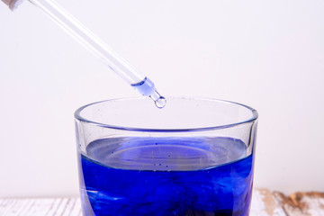 Pipette over a glass with blue liquid in the laboratory