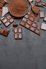 Dark or milk organic chocolate pieces and cocoa powder on dark concrete backgound