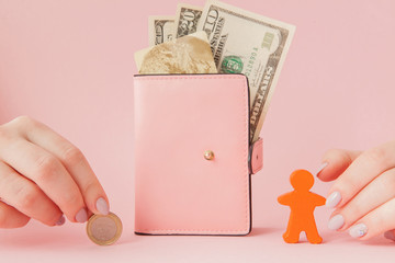 Bitcoin in a woman's hand and dollars in pink wallet with credit card on a pink background